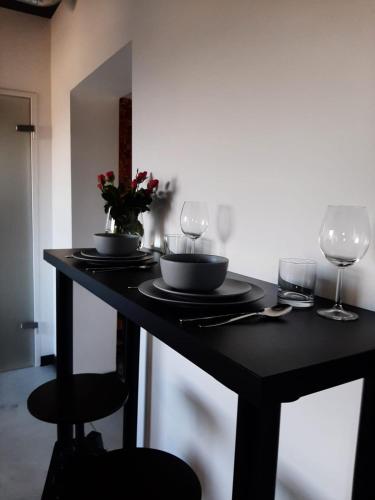 a black table with two wine glasses and a bowl and a plant at Apartamenty Gliwice Staromiejska 65 in Gliwice