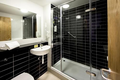 bagno piastrellato nero con lavandino e doccia di Holiday Inn Express Manchester Airport, an IHG Hotel a Hale