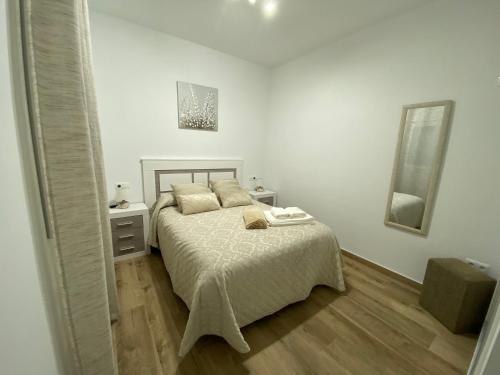 a white bedroom with a bed and a mirror at Ático CARMEN in Setenil