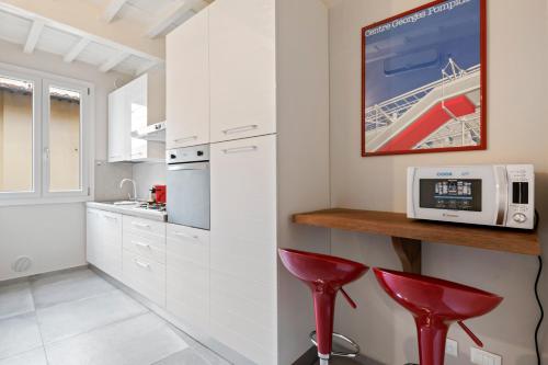 uma cozinha com armários brancos e bancos vermelhos em Il Palazzo della Signoria Modern Loft em Florença