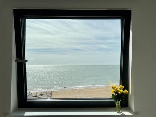 a window with a view of the beach with a vase of flowers at SoHot Stays Royal Sands Seaview Apt Free Parking Sleeps 4 in Ramsgate