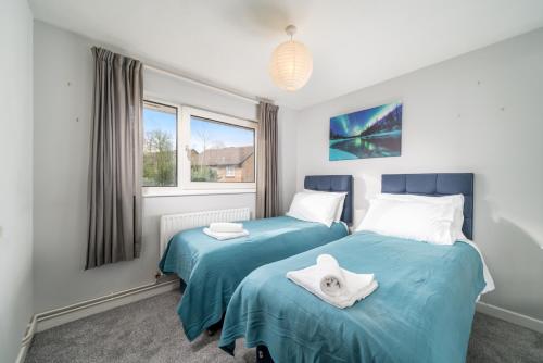 two beds in a bedroom with blue sheets at Spacious Pet-Friendly Apartment in Crawley by Sublime Stays in Three Bridges