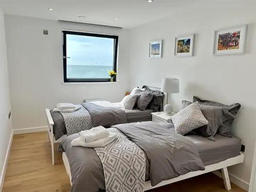 two beds in a room with a window at SoHot Stays Royal Sands Seaview Apt Free Parking Sleeps 4 in Ramsgate