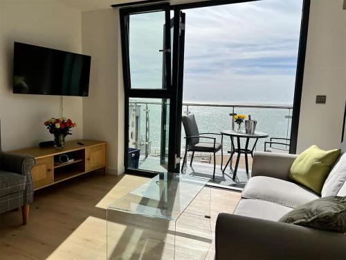 a living room with a couch and a television and a table at SoHot Stays Royal Sands Seaview Apt Free Parking Sleeps 4 in Ramsgate