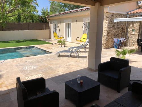 un patio avec des chaises et une piscine dans l'établissement Au milieu des Piboules de Provence., à LʼIsle-sur-la-Sorgue
