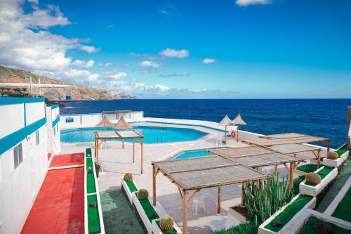 a swimming pool with tables and the ocean in the background at Marina Blue, Las Caletillas in Candelaria