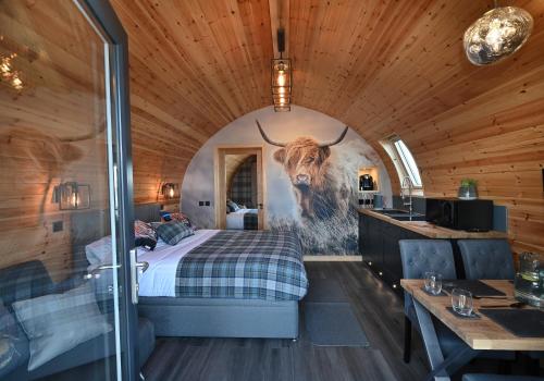 a bedroom with a bed with a painting of a bull at Pod 1, Sinclair bay lodges in Keiss