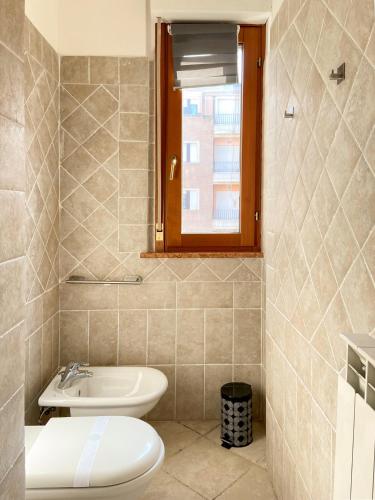 a bathroom with a sink and a toilet and a window at Suite Angeli, a due passi da Assisi in Santa Maria degli Angeli