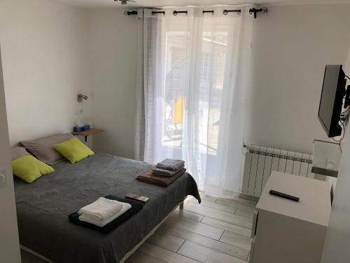 mała sypialnia z łóżkiem i oknem w obiekcie Au milieu des Piboules de Provence. w mieście LʼIsle-sur-la-Sorgue