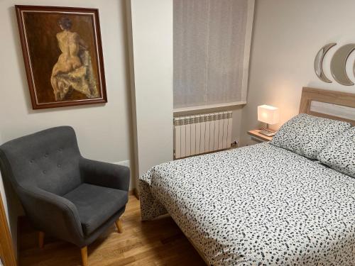 - une chambre avec un lit, une chaise et un tableau dans l'établissement AVA-1, à Arévalo