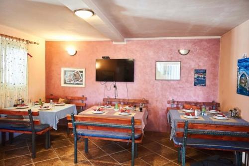 a restaurant with two tables and a tv on the wall at Skadar Lake Family Resort in Rijeka Crnojevića