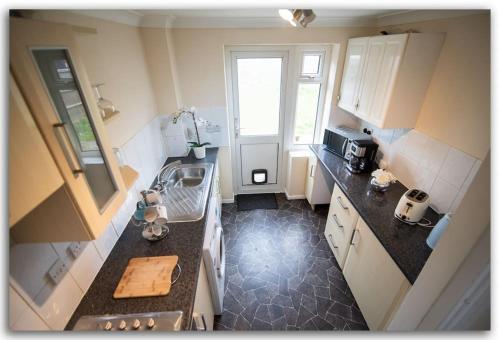 eine kleine Küche mit einem Waschbecken und einem Fenster in der Unterkunft BridgeCity Spacious Bartok House in the Heart of Basingstoke in Worting