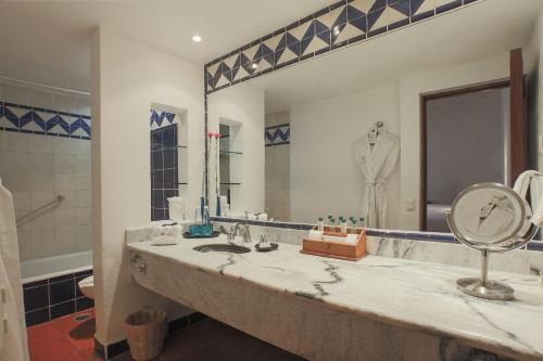 a bathroom with a sink and a large mirror at Quinta Real Oaxaca in Oaxaca City