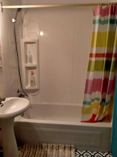 y baño con bañera, lavamanos y cortina de ducha. en apartment avec parking privé en Quebec