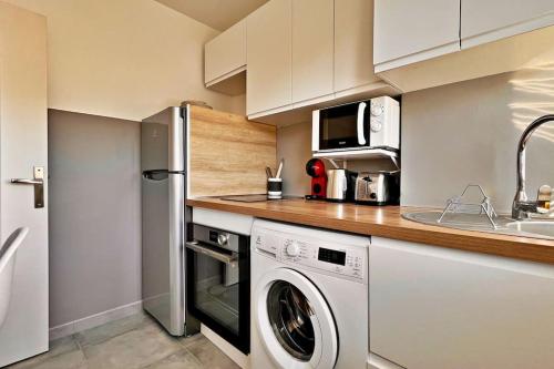 une cuisine avec un lave-linge et un micro-ondes dans l'établissement L'Azur Plaisance, à Nice