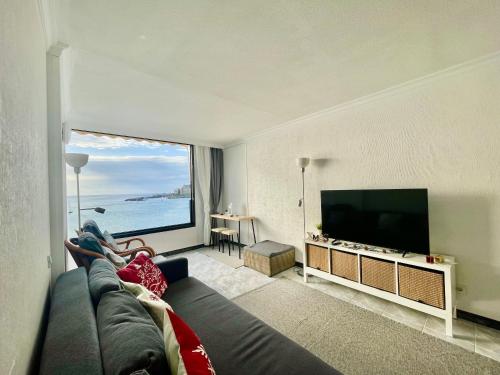 een woonkamer met een bank en een groot televisiescherm bij Direkt am Strand - Playa Patalavaca - Doñana in Patalavaca
