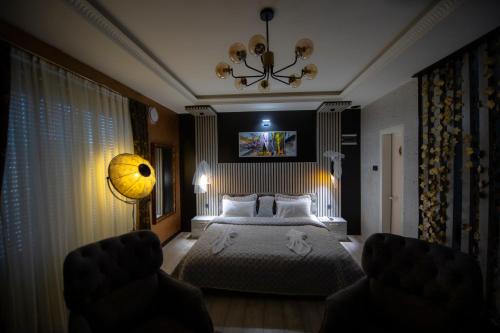a bedroom with a bed and a chandelier at Hotel and Apartments Central City Prishtina in Prishtinë