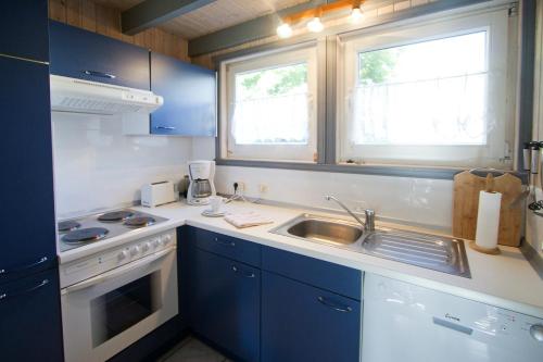 cocina con armarios azules y fregadero y 2 ventanas en Ferienhaus Mirow 66, en Mirow
