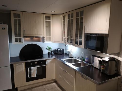 a kitchen with white cabinets and a black counter top at Malvik in Malvik