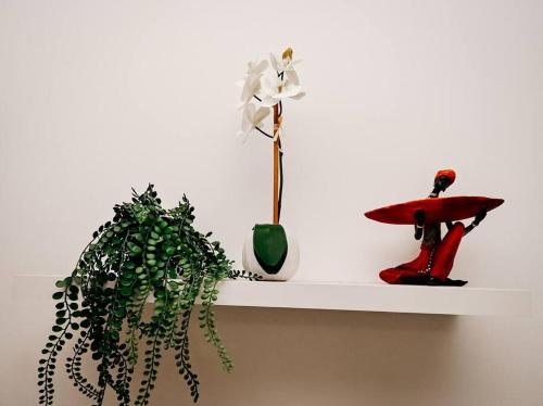 a white shelf with a plant and a vase on it at Secure and comfortable , Fully equipped Unit in Lombardy East