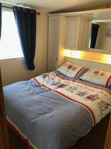 a bedroom with a bed with a blanket on it at Parkdean Resorts Bideford Bay Bucklands 21 in Bideford