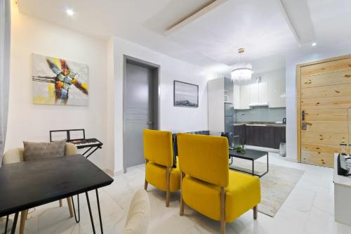 a living room with a dining table and yellow chairs at Exclusive Upscale 1 Bedroom Apartment in Lekki phase 1 in Lagos