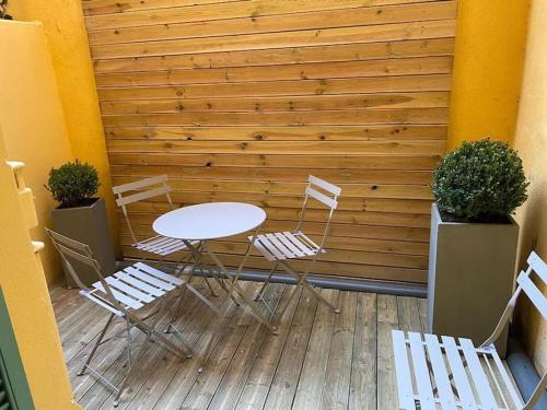 uma mesa e cadeiras num pátio com uma parede de madeira em Beau studio, 2min walk Monte Carlo Casino, terrace em Beausoleil