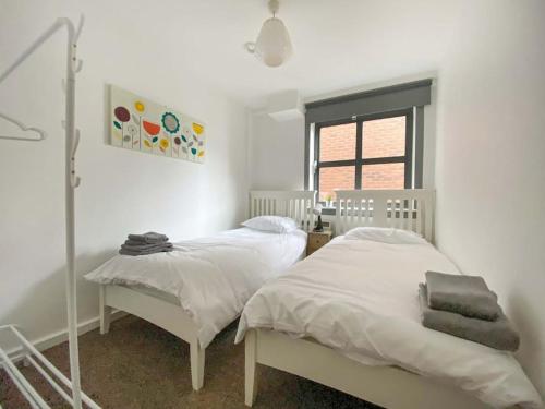a bedroom with two beds and a window at Beautifully Presented 2 Bedroom Apartment in Liverpool