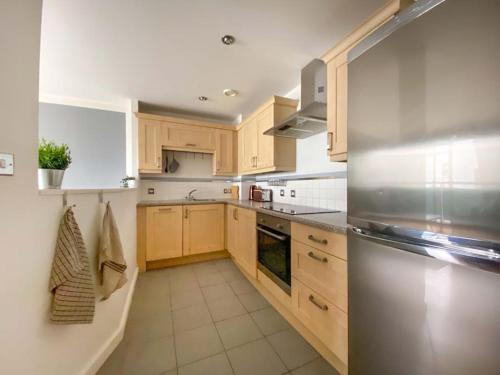 a kitchen with wooden cabinets and a stainless steel refrigerator at Liverpool One Beautifully Presented 2 Bedroom Apartment in Liverpool