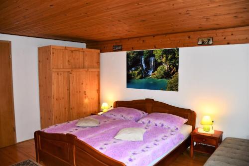 a bedroom with a purple bed with a picture on the wall at Apartments Lenc in Bovec