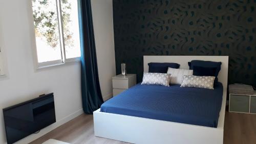um quarto com uma cama azul e uma janela em Appart. vue et accès mer à l'entrée du cap Corse em Marine du Miomo