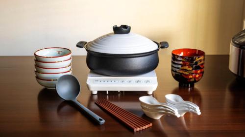 a pot on a stove with dishes and spoons at OriOri House Hotel Mt Fuji view 全室富士山ビューの貸切り宿 折々 in Fujikawaguchiko