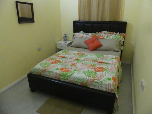 a small bedroom with a bed with a orange pillow at Southern Haven Guesthouse in Laborie