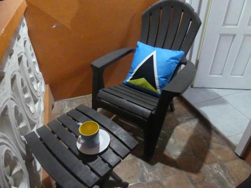 a black rocking chair with a cup of coffee on a table at Southern Haven Guesthouse in Laborie