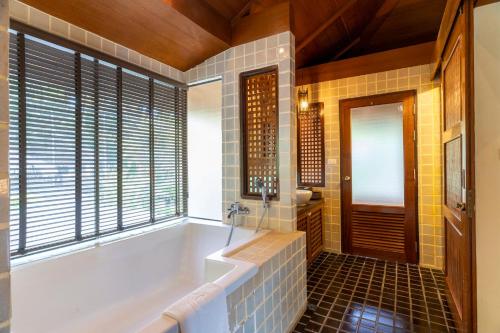 a bathroom with a tub and a window at Centara Koh Chang Tropicana Resort in Ko Chang