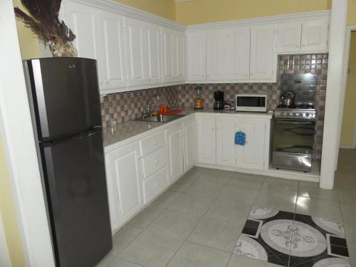 a kitchen with white cabinets and a black refrigerator at Southern Haven Guesthouse in Laborie