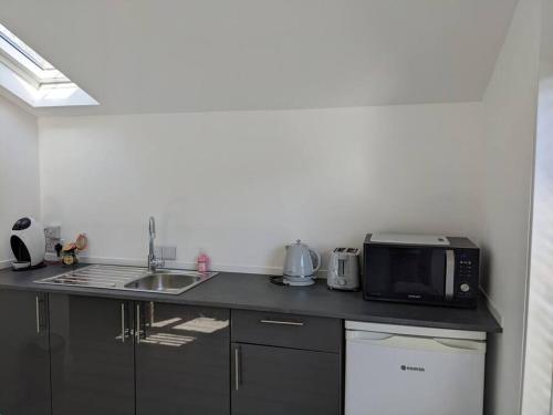 a kitchen counter with a microwave and a sink at Seaside guest house a stone's throw from the beach in Dawlish