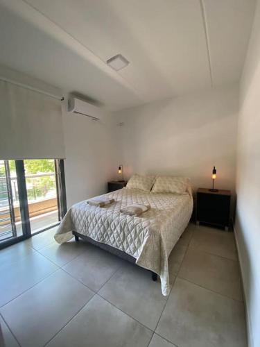 Dormitorio blanco con cama y ventana grande en Departamento Azopardo, Godoy Cruz Mdz en Godoy Cruz