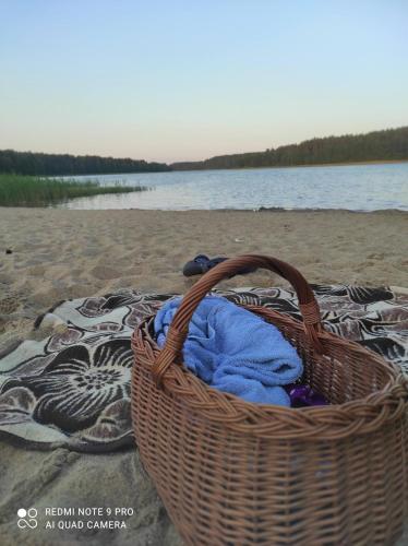 a basket sitting on a beach with a towel at Rykowisko - domki całoroczne nad jeziorem i rzeką in Szczecinek