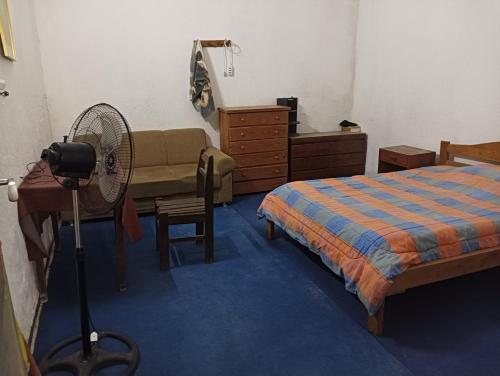 um quarto com uma cama, uma secretária e uma ventoinha em La Casa De Seba em Montevidéu