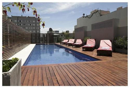 una piscina con sillas y una terraza de madera en Departamento con pileta Almagro en Buenos Aires