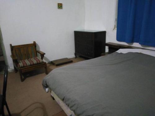 um quarto com uma cama, uma cadeira e uma janela em La Casa De Seba em Montevidéu