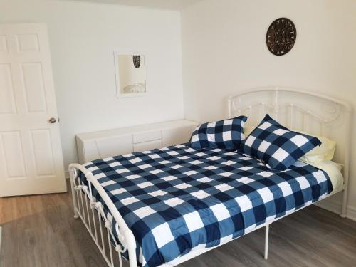 a white bed with a blue and white checkered blanket at A&I Cosy&Bright Apartments near Old Port and South Shore in Longueuil