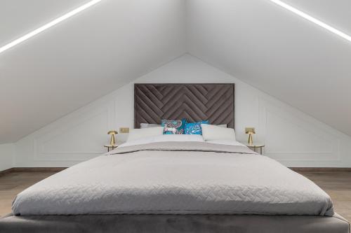 a white bedroom with a large bed in a attic at Amber Stone Apartment 2nd floor in Palanga