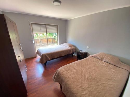 a hotel room with two beds and a window at Casa amoblada, Los Vilos in Los Vilos