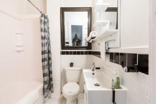 y baño con aseo, lavabo y espejo. en MtlVacationRentals - Appartements Plateau-Mont-Royal, en Montreal