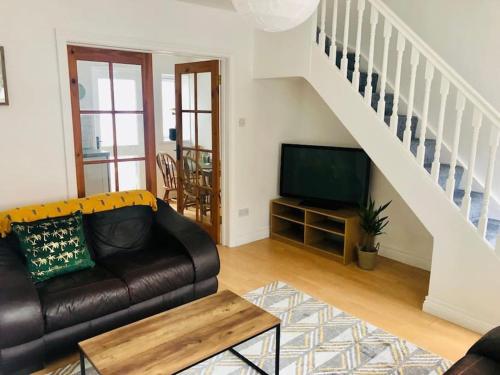 a living room with a leather couch and a tv at Cosy House, Lisburn Road in Belfast