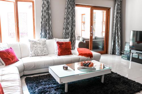 a living room with a white couch and a coffee table at Modern Home in Pretoria in Pretoria