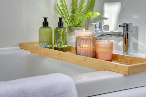 a bathroom sink with two bottles of soap and candles at Regency Nest by Spa Town Property - Stylish 3 Bedroom Apartment on 2 Floors, Central Leamington Spa in Leamington Spa