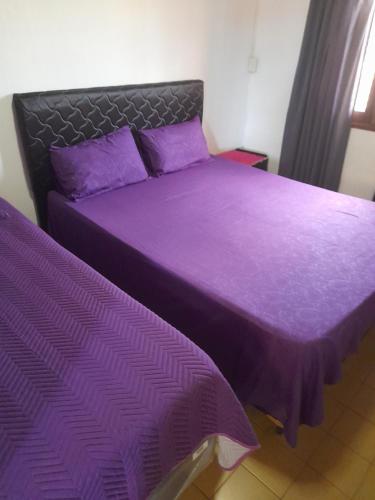 two beds with purple sheets in a bedroom at AparWil in Encarnación